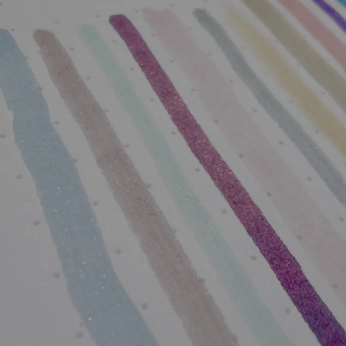 Colourful, glittery ink swatches on white paper.
