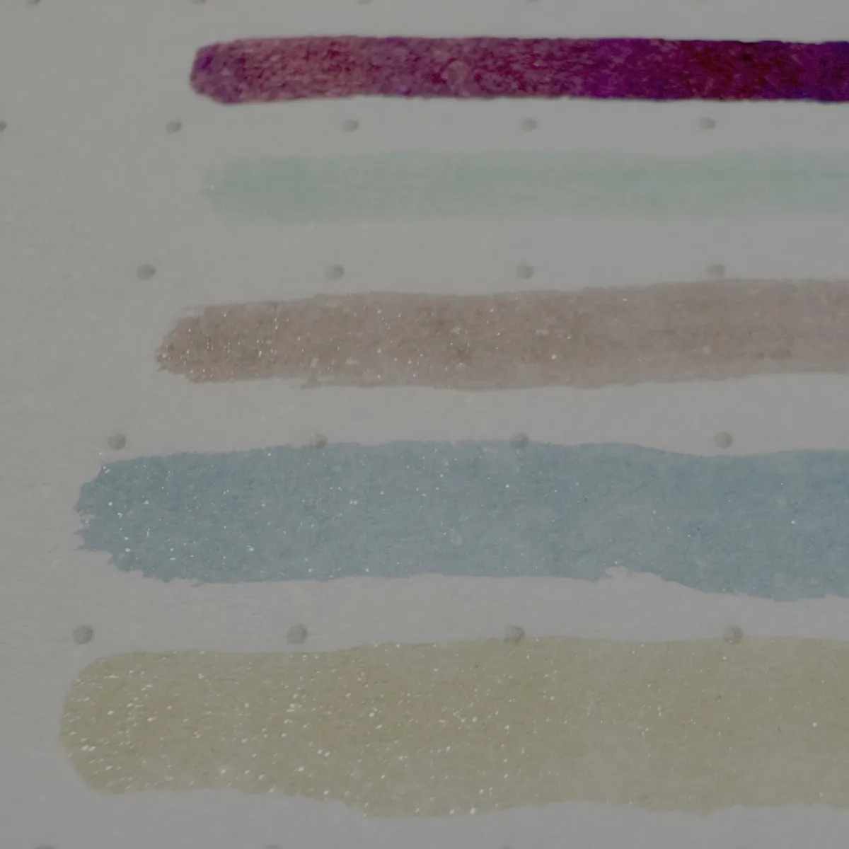 Colourful, glittery ink swatches on white paper.