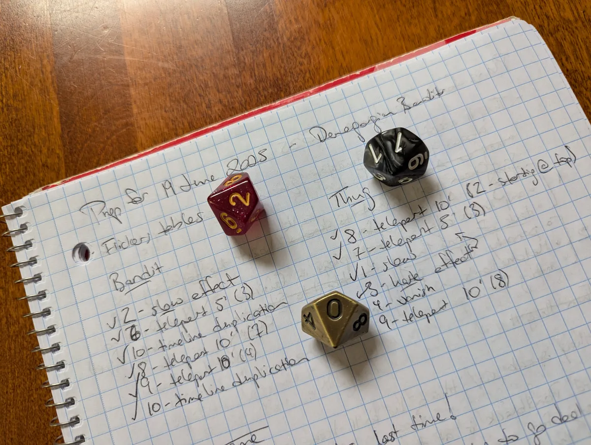 three ten-side dice, from different sets, sit on a notebook in which is written preparation for an encounter, including two sets pre-rolled results from a table