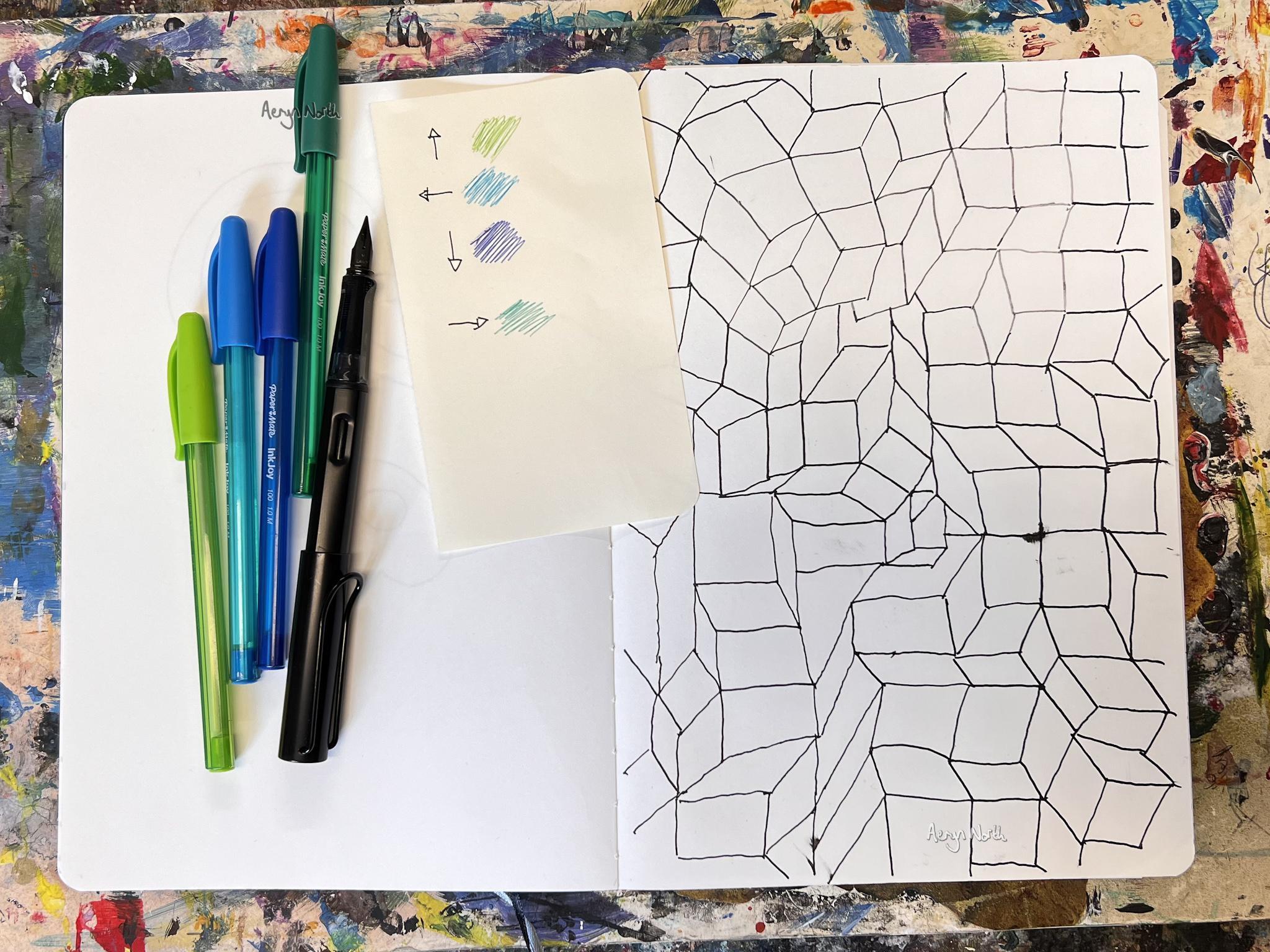 An open notebook is positioned on a colorful, vibrant background. The artwork in the notebook is a geometric pattern consisting of black lines and shapes. On the left side of the notebook, there are several pens and a sheet of paper with clouts and arrows on it.