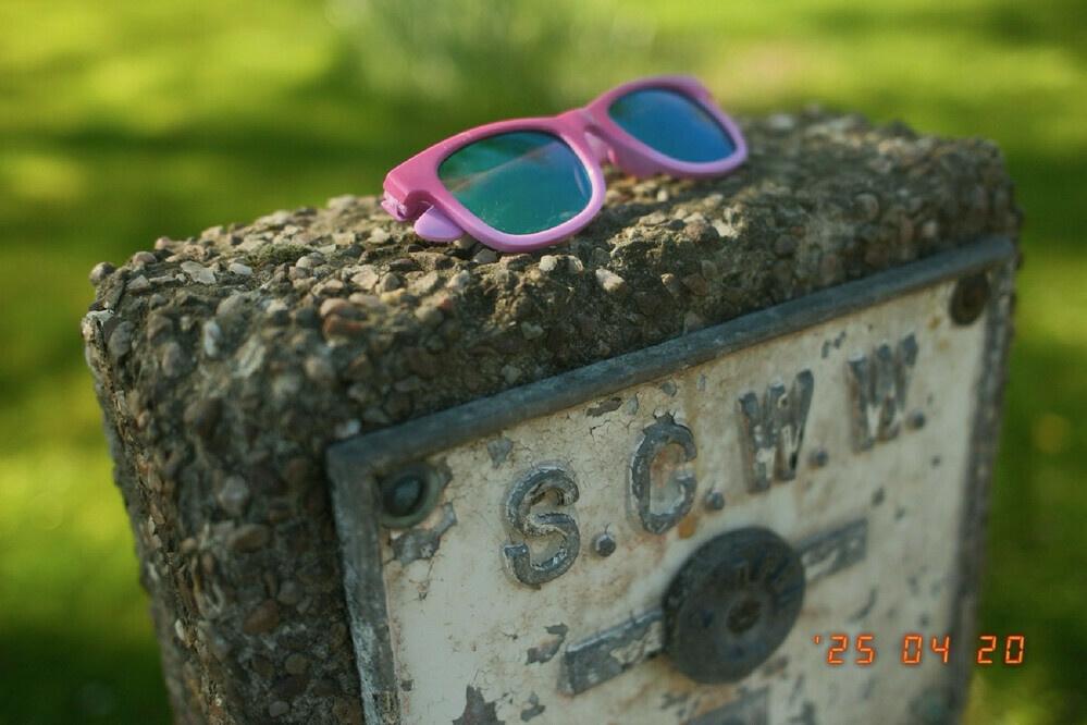 A pair of pink sunglasses on top of a concrete sign.