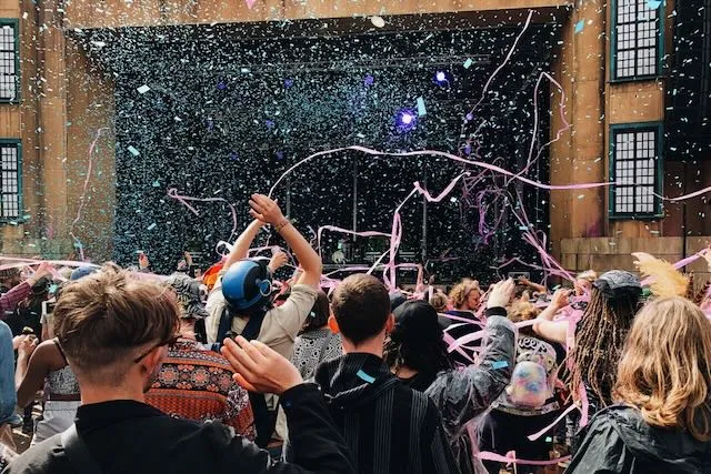 Pink streamers and confetti above the crowds at a festival