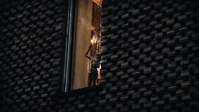 A small child touches a window with rain pouring down it