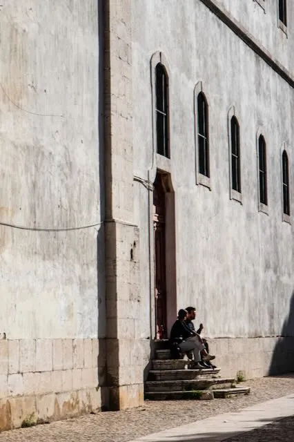 a pair of people eat lunch on the steps of an old building