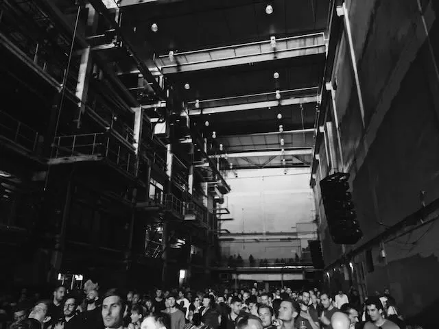 A crowd of people watch a show in a huge room in black and white