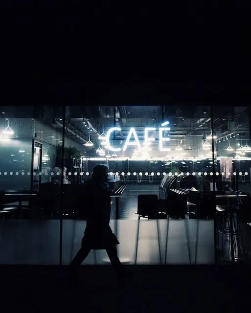 A person walks before a cafe at night