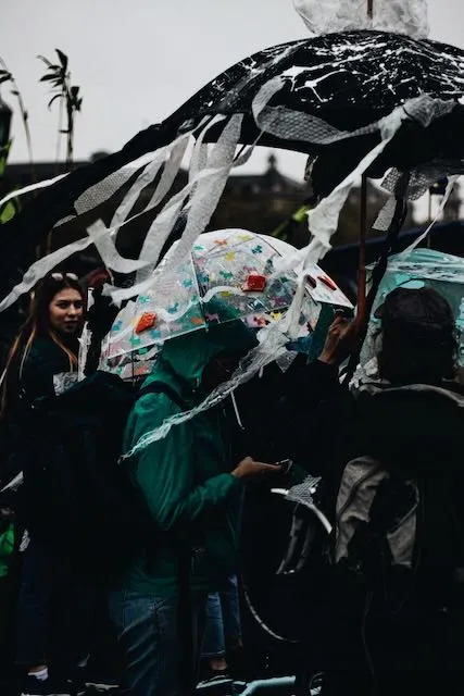 People shelter from the rain beneath creatively adorned umbrellas