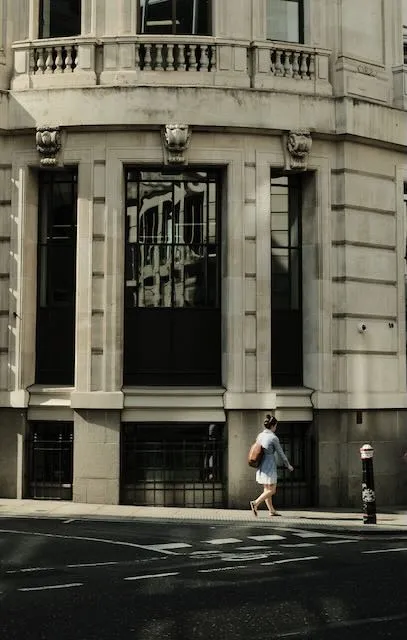 A woman walks down a mosty deserted street in summer.