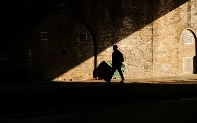 A sihlouette of a man walks through a well-fitting shard of light.