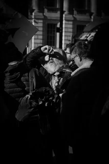A man shields his eyes from the sun in black and white