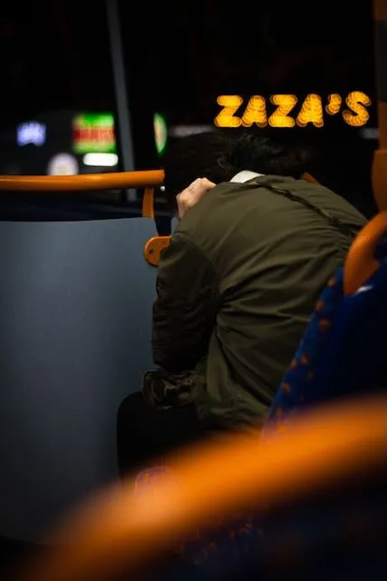 A woman clutches her head on a bus, a sign saying Zaza is visible in the background