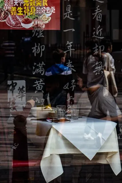 Two women enjoy lunch through a window covered in chinese characters