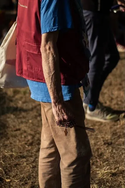 A mans hand clutches incense and rosary beads