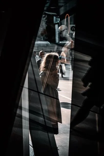 A person on the phone seen through two layers of glass, reflecting the movements of others
