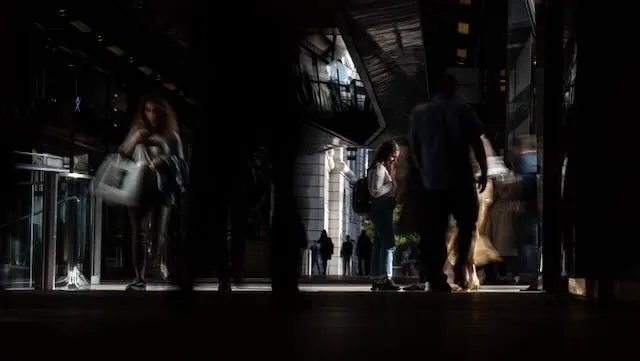 A long exposure of people moving around with one person in focus in the middle