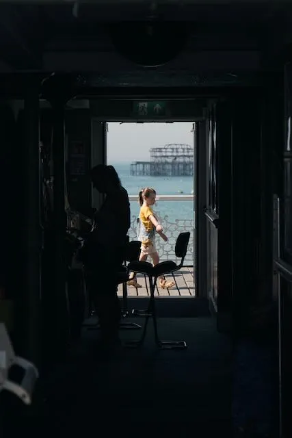 A young girl in yellow is seenthrough the frame of a corridor at the seaside.
