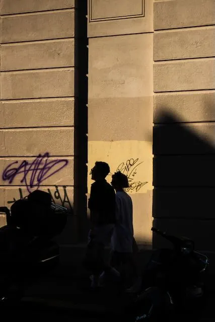 Two people are sihlouetted against a brick wall at sunset