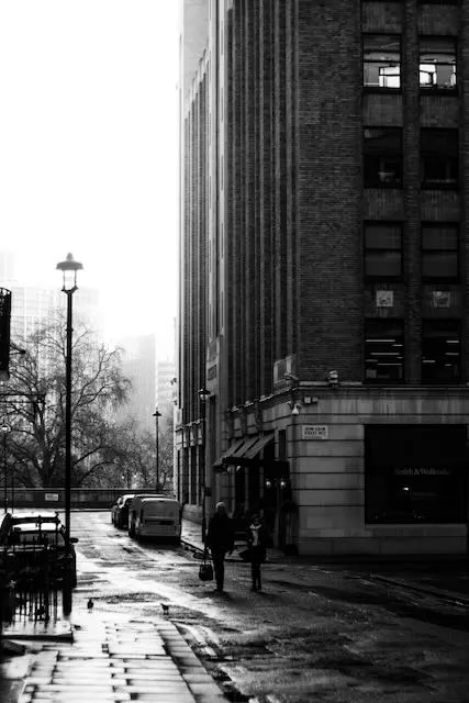 Two people walk down a street in bright sunlight on new year's eve