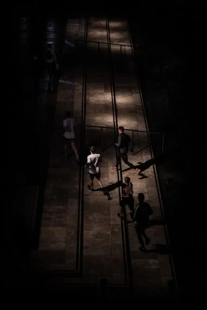 a group of runners pass some steps, lit by horizontal sweeps of light