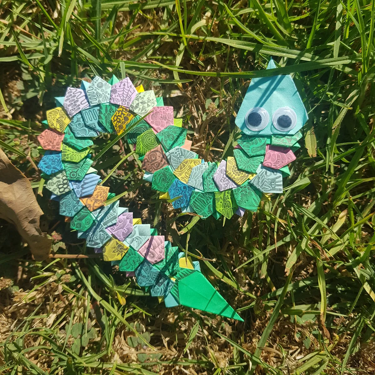 serpiente colorida de origami con dibujitos tatuados a lápiz