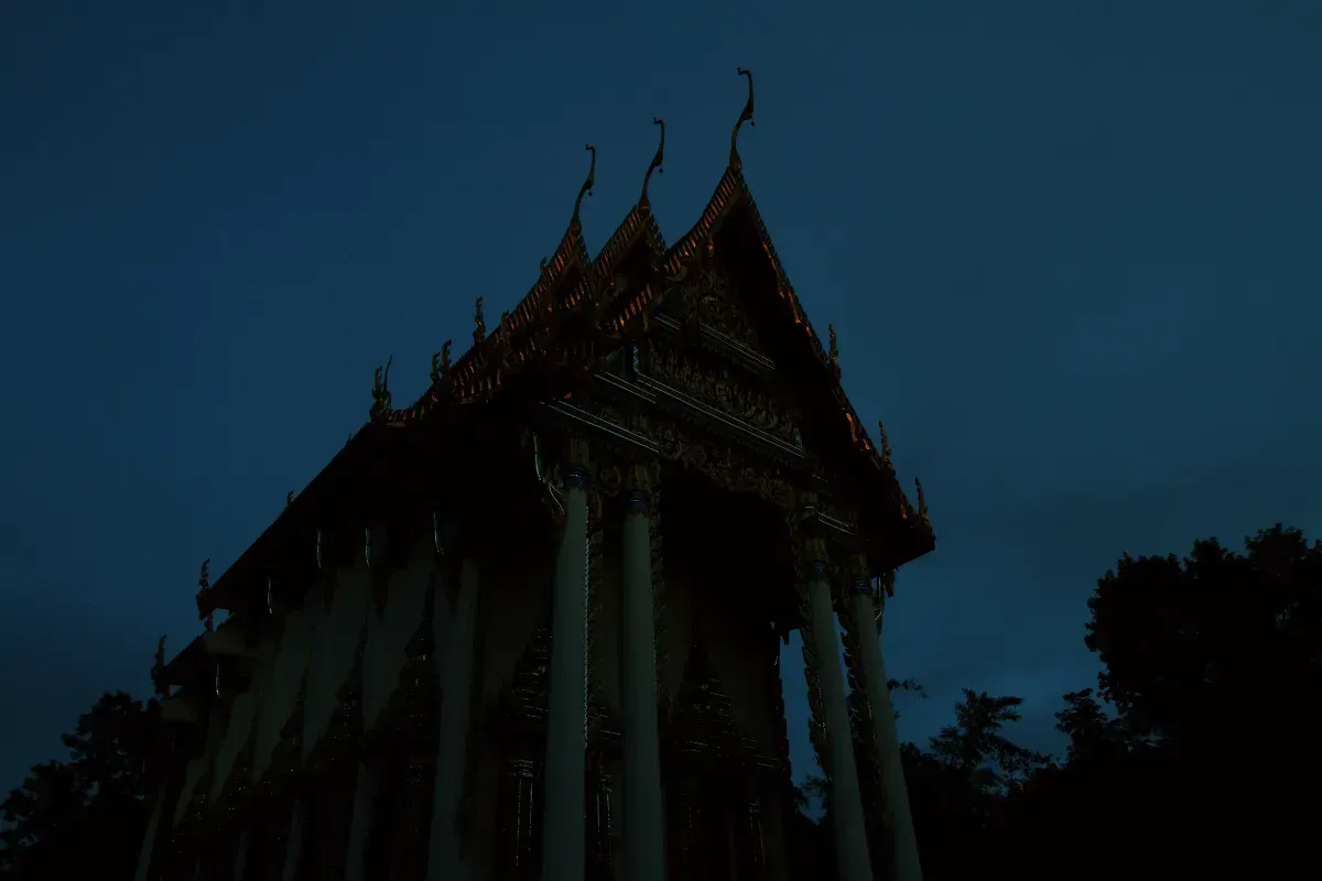 Traditional Thai temple silhouetted against the evening sky.