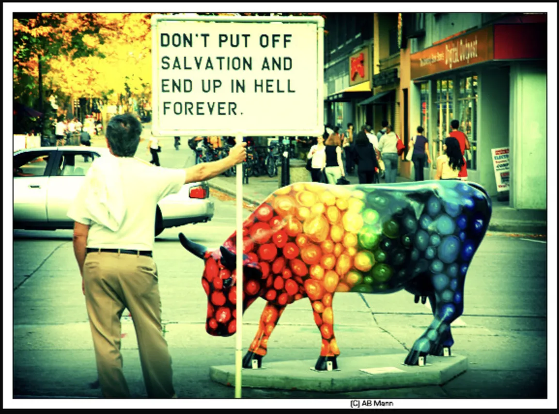 Photo of a hellfire preacher with a sign condemning people to hell while standing next to a very gay bull