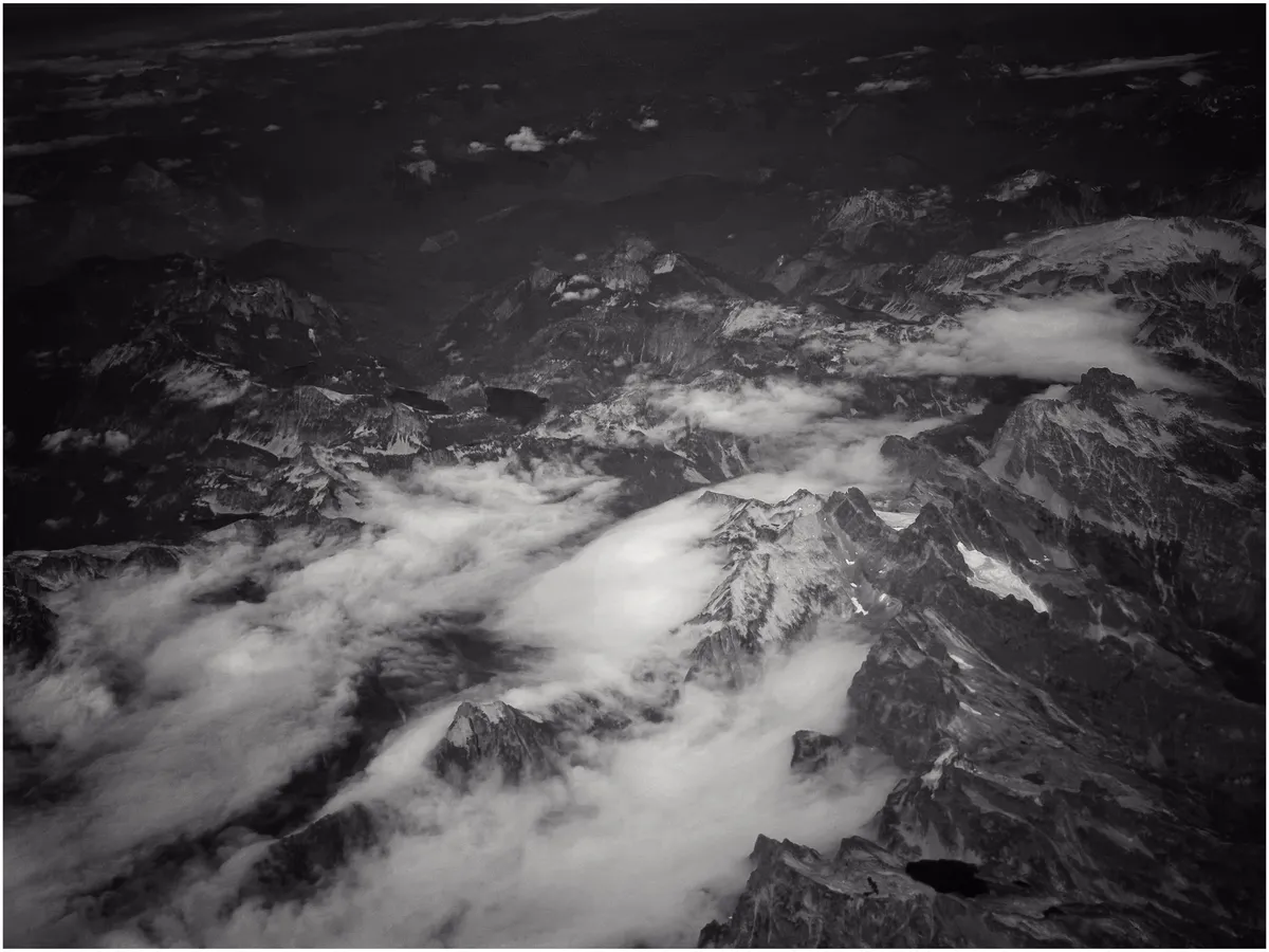 Overhead shot of a rocky mountain ridge. Peaks peek through the clouds.