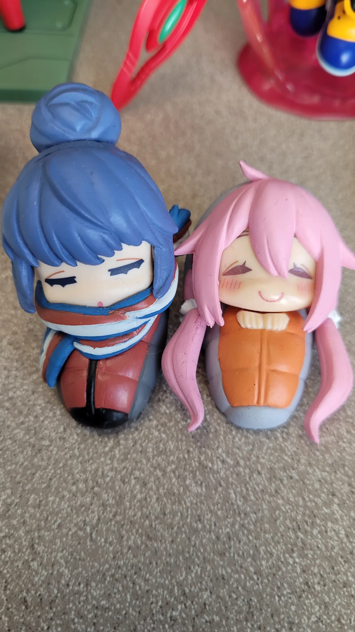 Rin and Nadeshico figures, bundled up in scarves and sleeping bags, sleeping