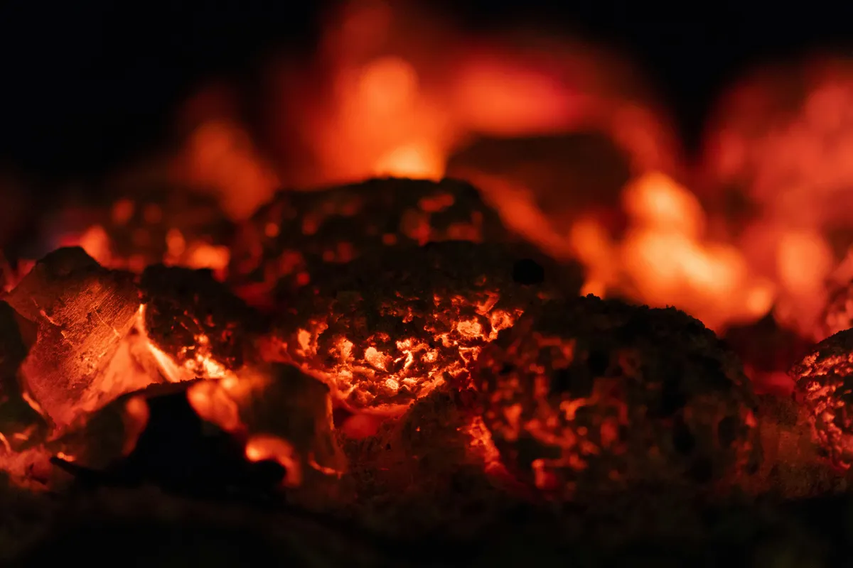 A close up of coals glowing with inner warmth against a dark background