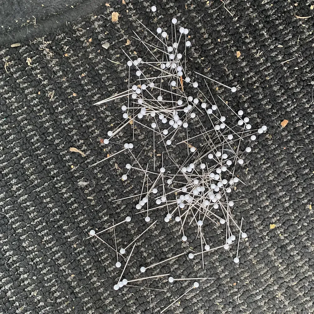 Pile of long push pins spilled on the car floor.