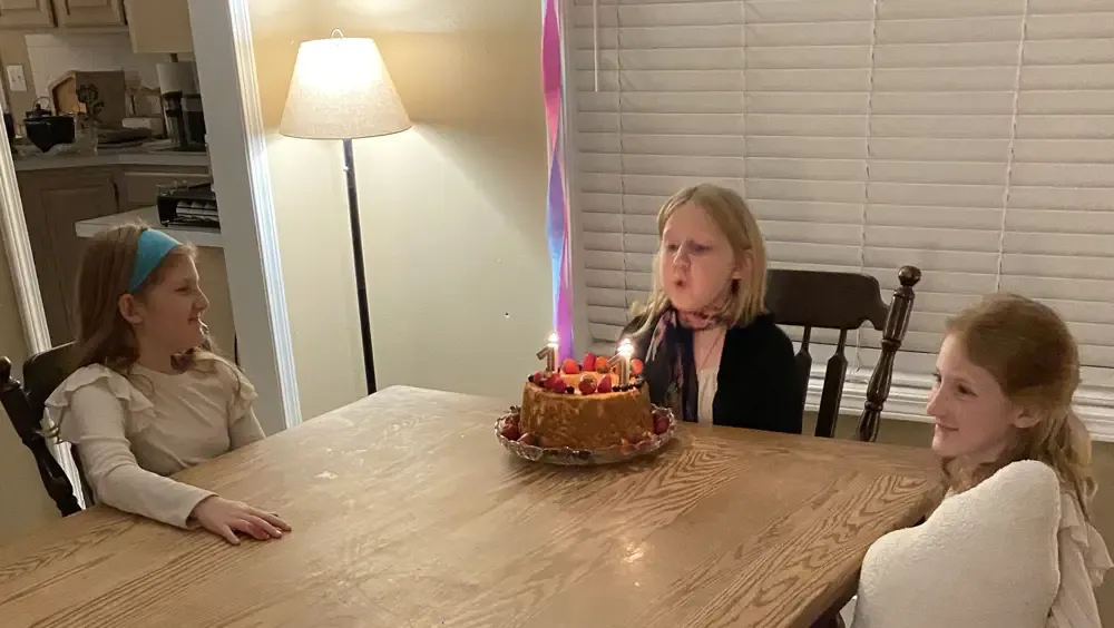 S blowing out the candles on her angel food birthday cake.