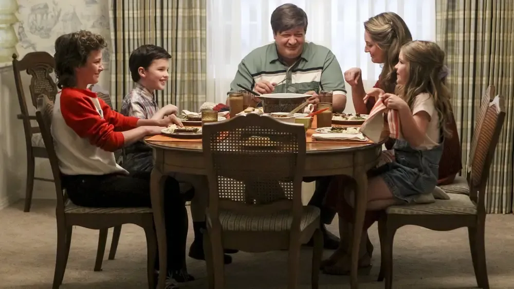 Sheldon shares a laugh with his family around the dining room table.