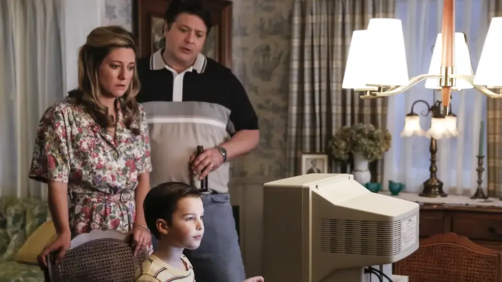 Mary and George look over Sheldon's shoulder as he uses the new family computer.