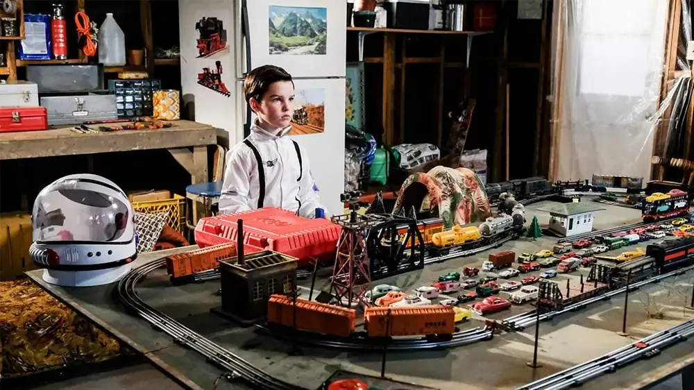 Sheldon space-suited up and playing withi his trains in the sealed off garage.