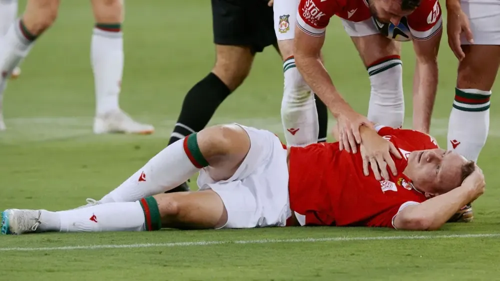Paul Mullin lies on the pitch as one of his teammates checks on him.