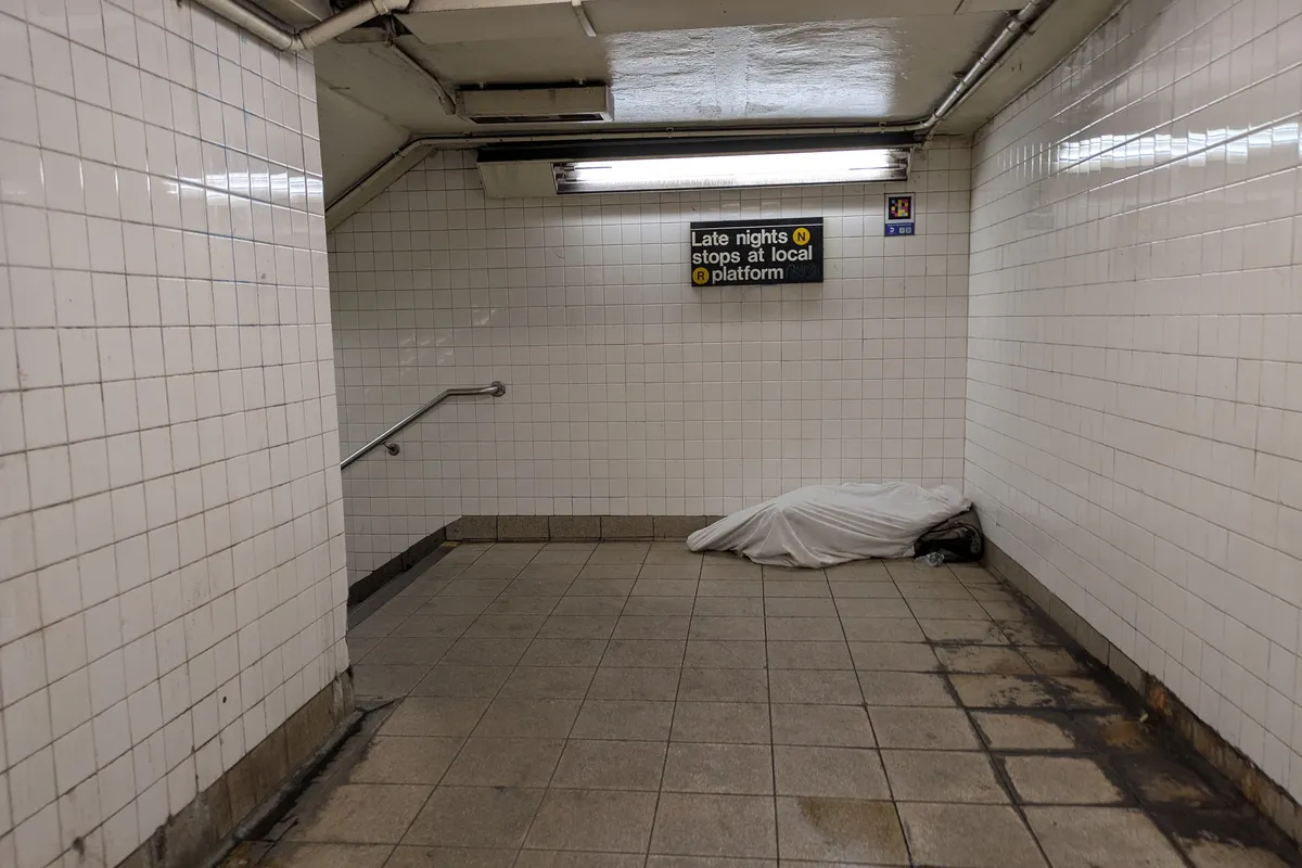 person sleeping covered by a sheet in the metro stairs