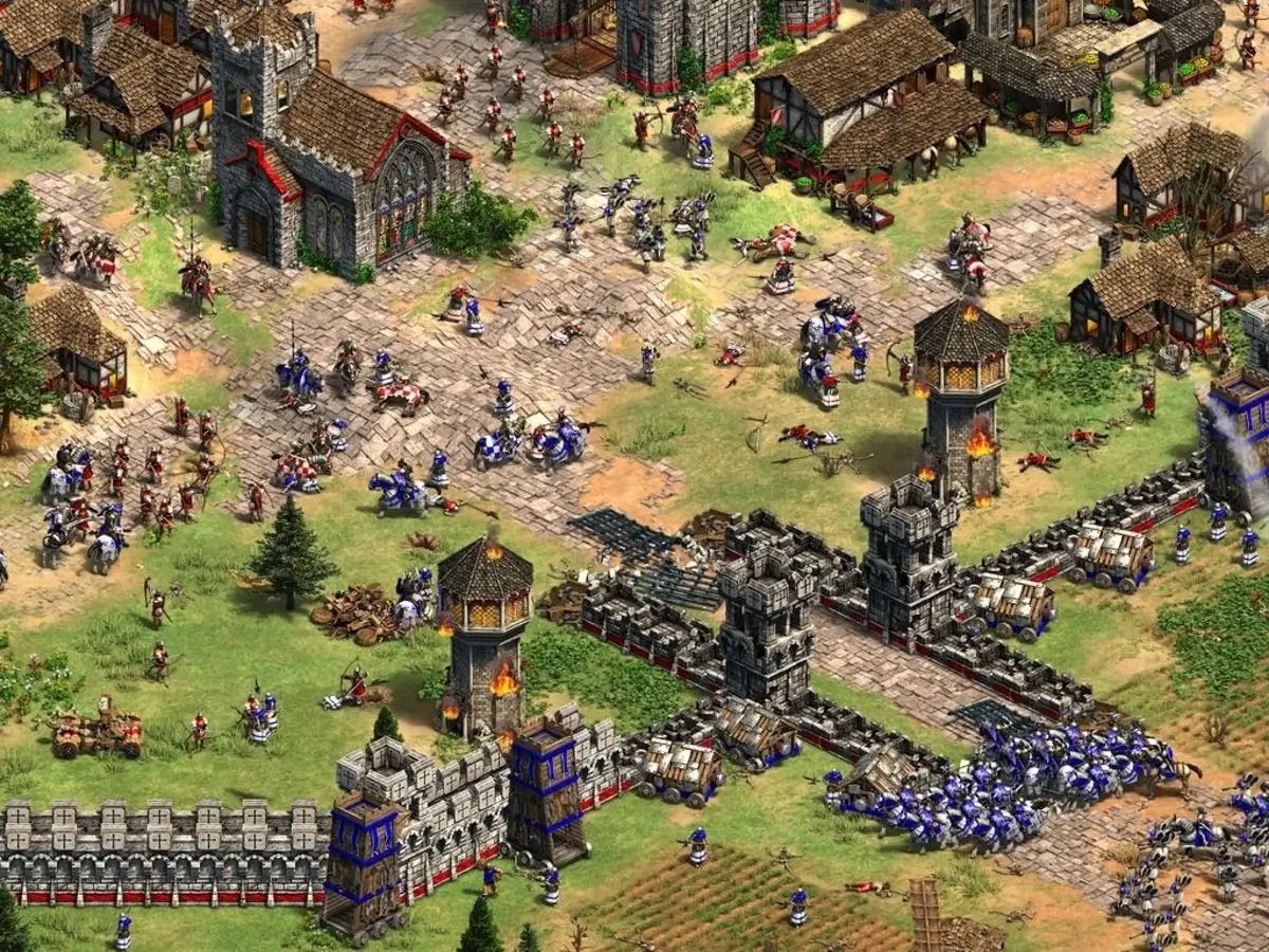 Screenshot of Age of Empires II: Definitive Edition showing a town being invaded by enemy soldiers.