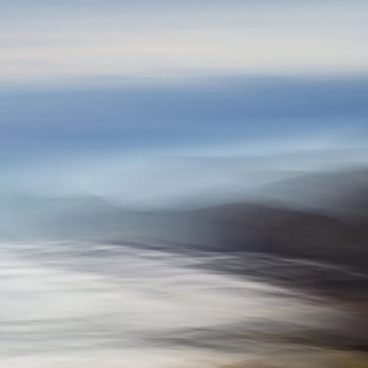 abstracted coastal view with ghostly after-images in dark tones suggesting the cliffs and headlands, while wispy ocean whites, blues and greens sweep into their feet. Above is a band of mostly blue sea beyond the headlands, fading into lighter white tones of some clouds above