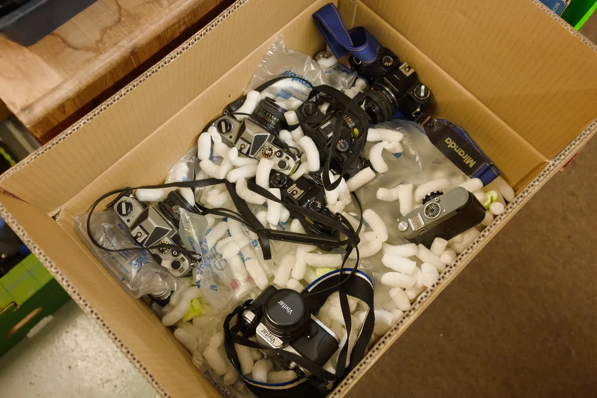 A number of film SLRs being unpacked from a box