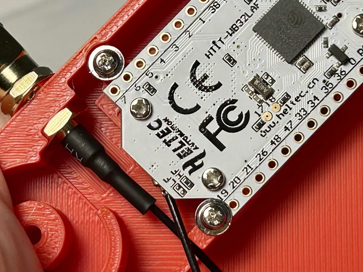 A Heltec v3 board held by screws inside a case