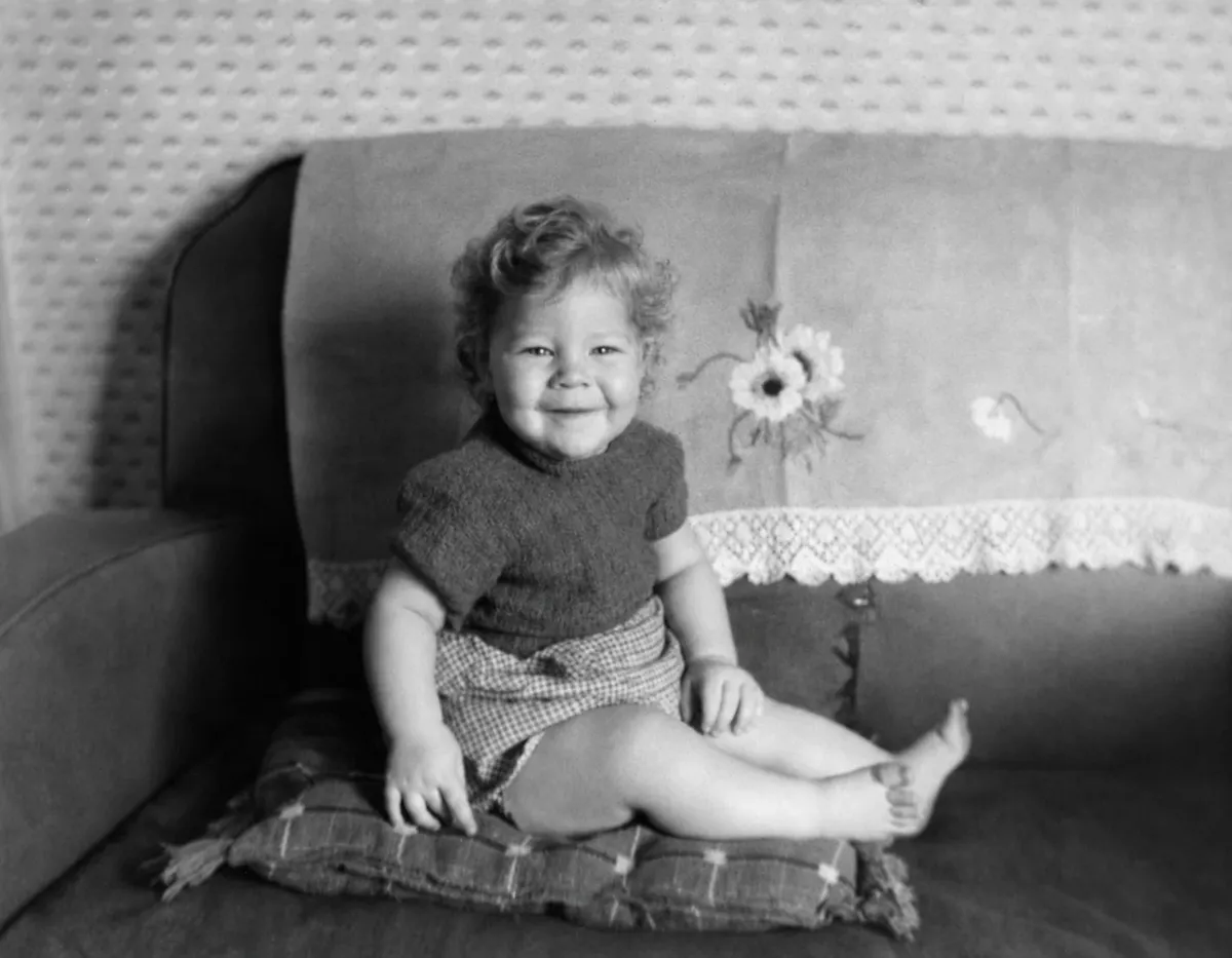 Toddler sitting on a sofa 1960s