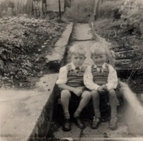Two brothers dressed up for Whitsun, sitting on back garden steps. The photo was taken around 1960