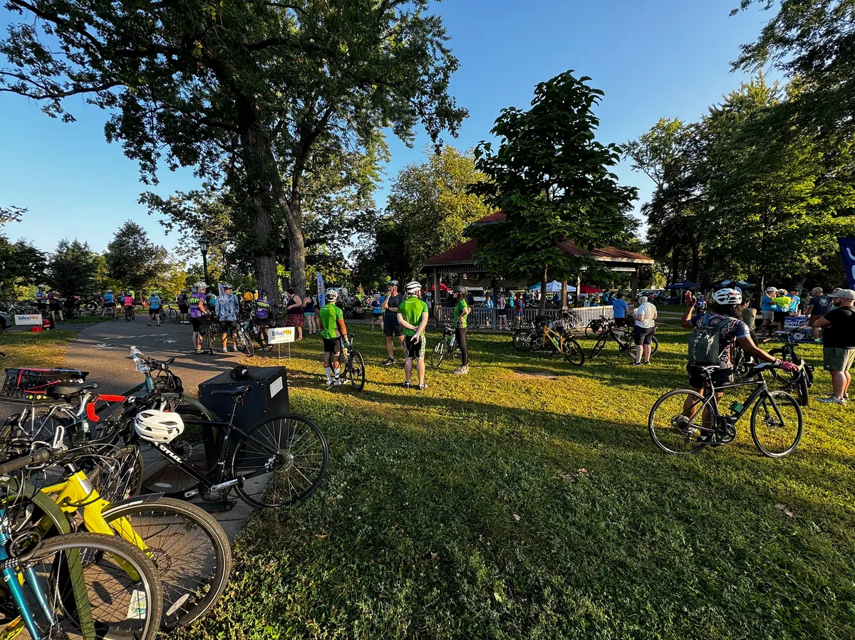 Bicycle riders standing in a park waiting for a group ride.