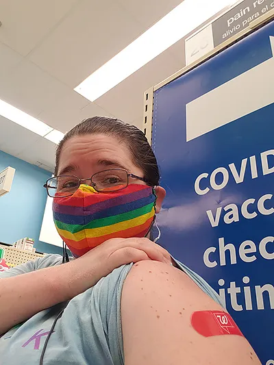 an ouchie that's well worth it: me in my rainbow facemask and a bandaid on my upper arm