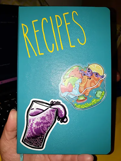 a teal journal labelled 'recipes' and covered in stickers