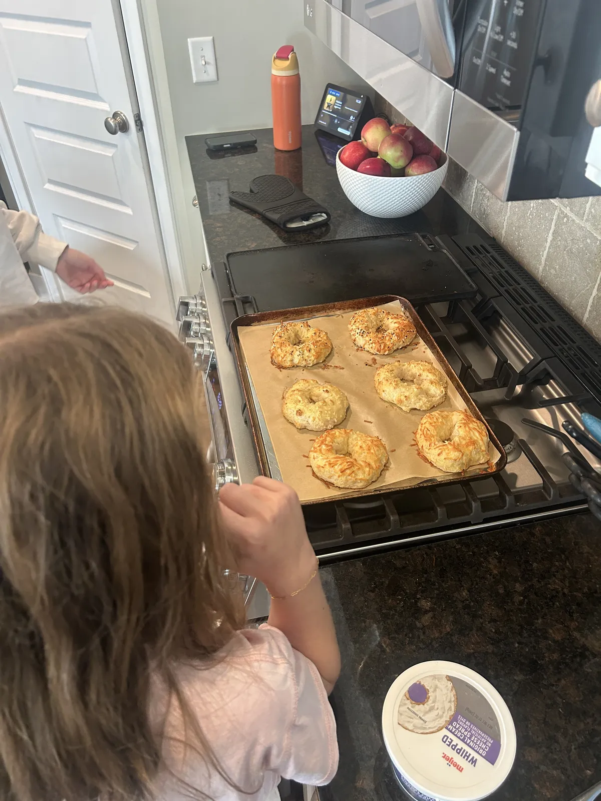 A tray of bagels cooling on the stove.