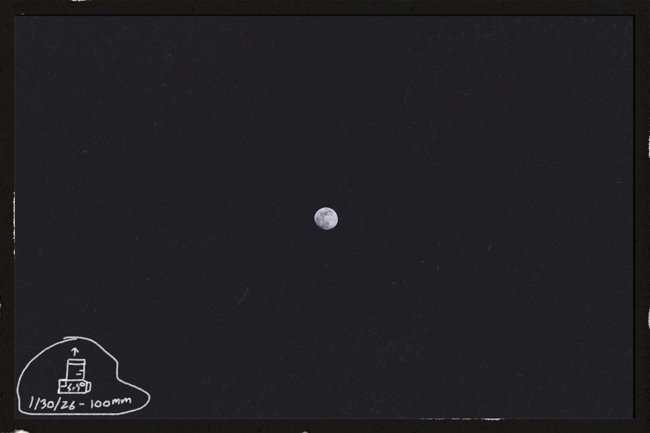 Photo of the moon in the distance - handwritten in the lower left of the frame is '01/30/26 100mm' with a badly drawn camera