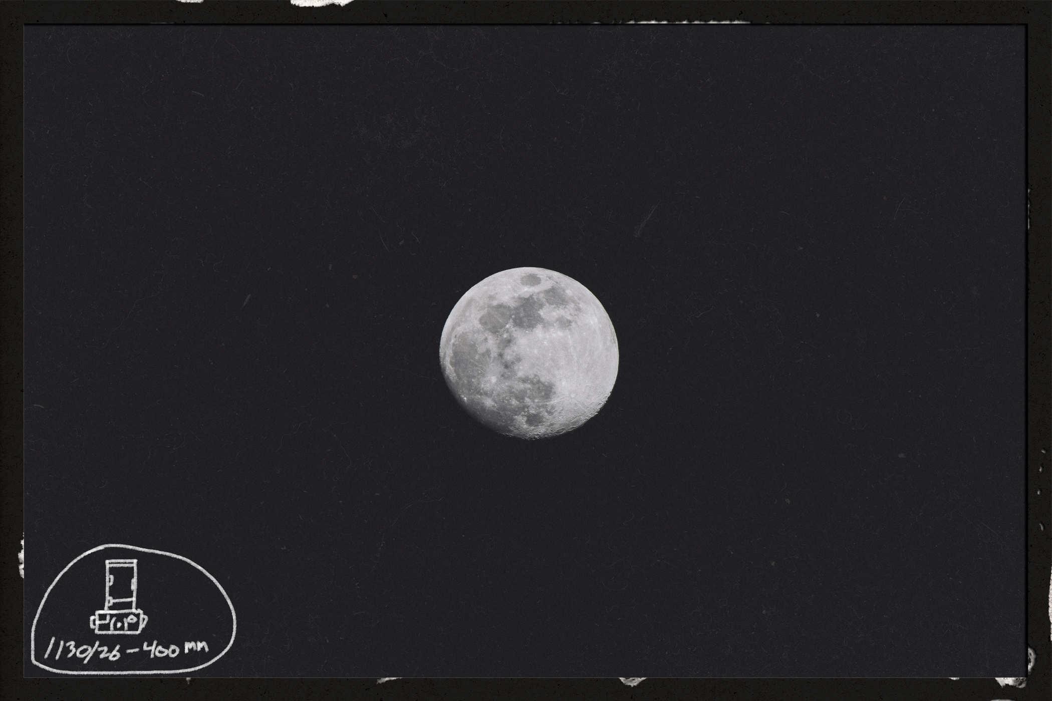 Photo of a near full moon; handwritten in the lower left of the frame is '01/30/26 400mm' with a badly drawn camera