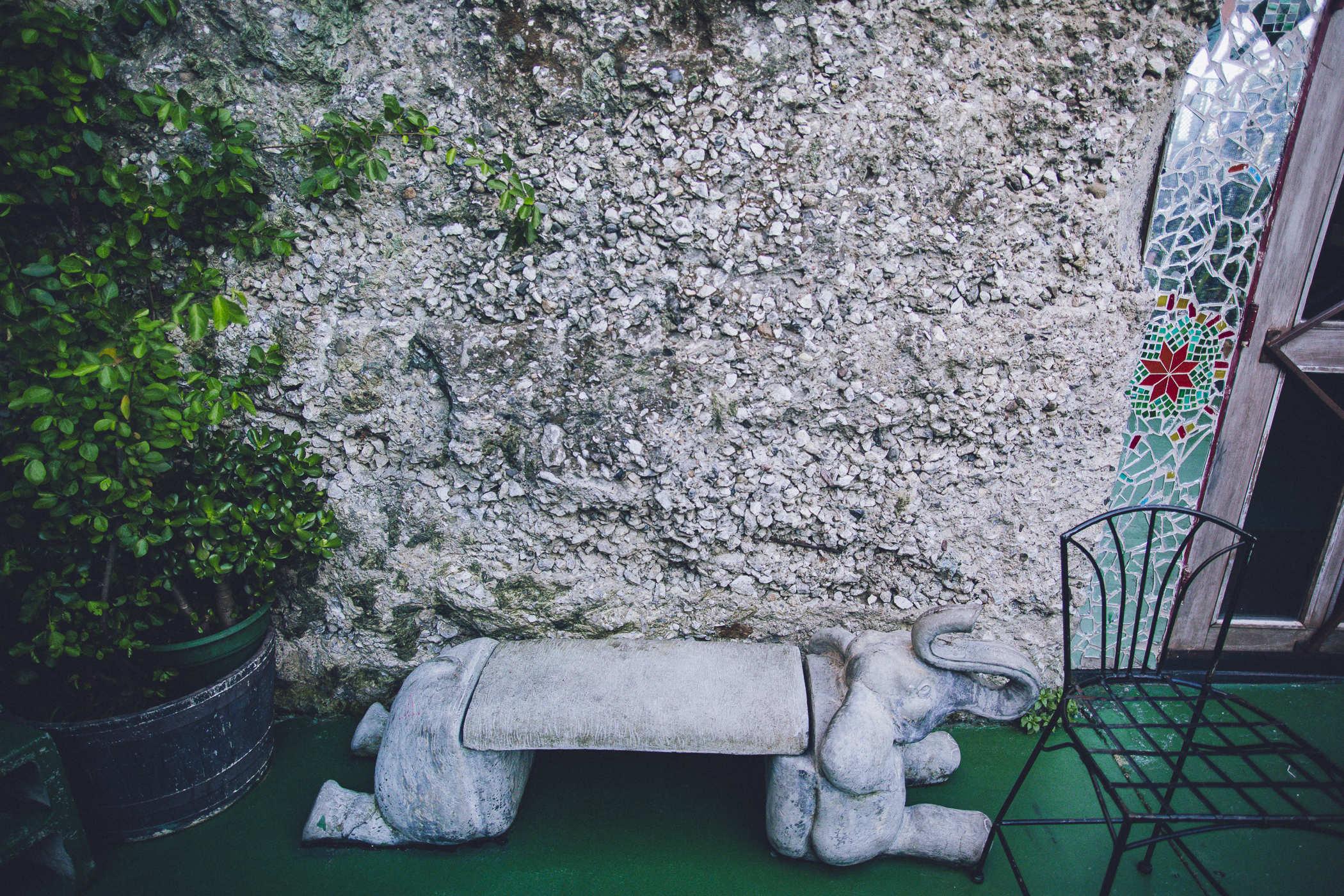 Photo of an outdoor patio with a stone bench with an elephant's head and legs caved on the edges