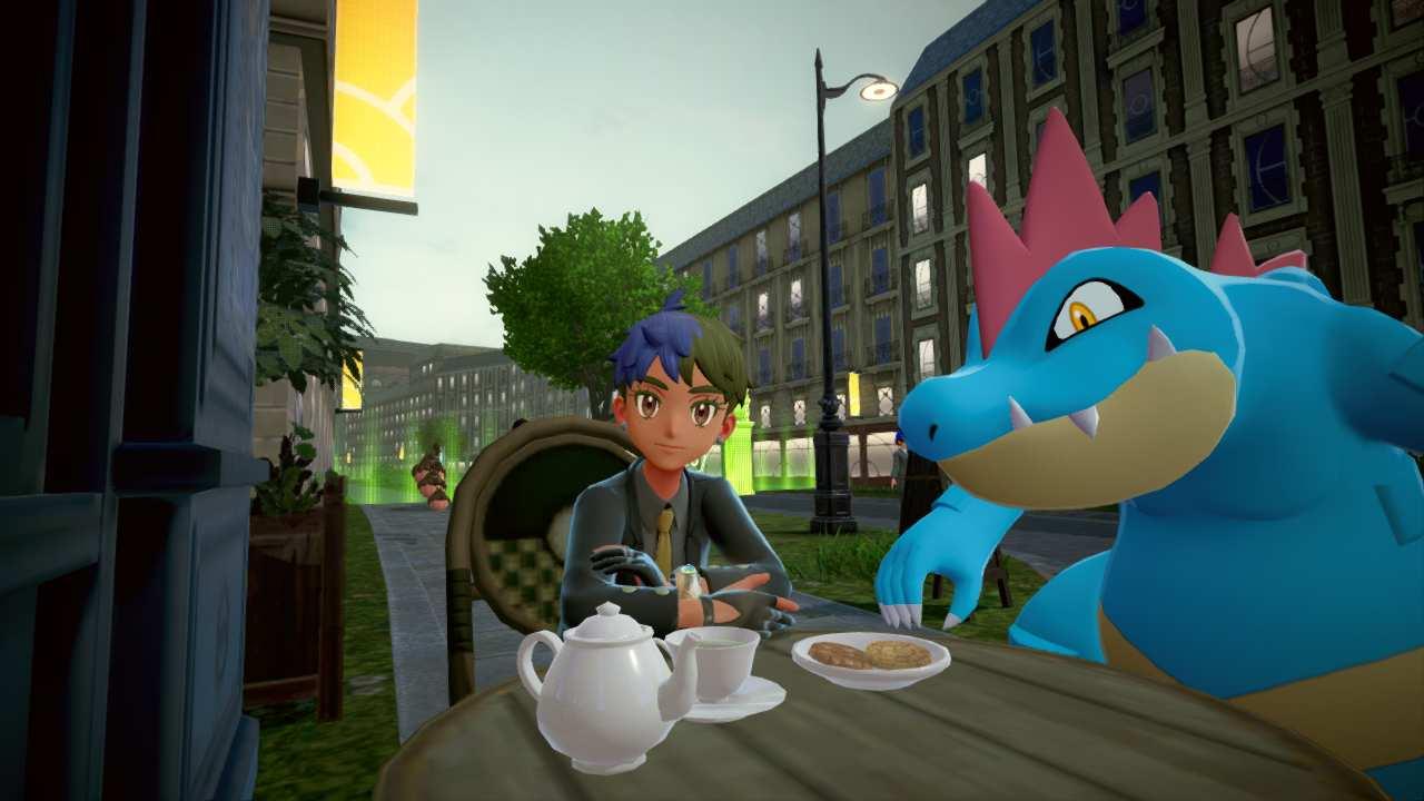 A person with blue and green hair sitting at a cafe table with a teapot and a cup of tea; there's an ominously large blue dinosaur sitting next to them; they're both looking at the camera